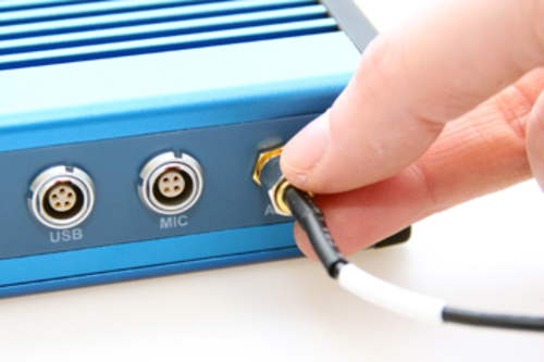 Photograph of a hand connecting the antenna cable to the antenna port on the VBOX Video HD2.