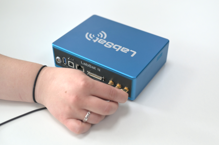 Photograph of a hand connecting the antenna to the RF IN port.