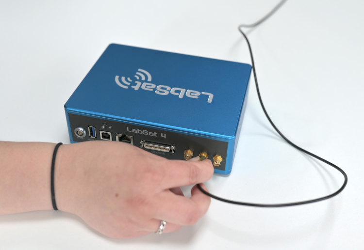 Photograph of a hand connecting an antenna to the RF OUT port.