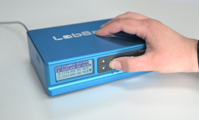 Photograph of a hand pressing a button on a LabSat 4.