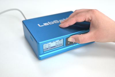 Photograph of a hand pressing a navigating the menu on a LabSat 4.